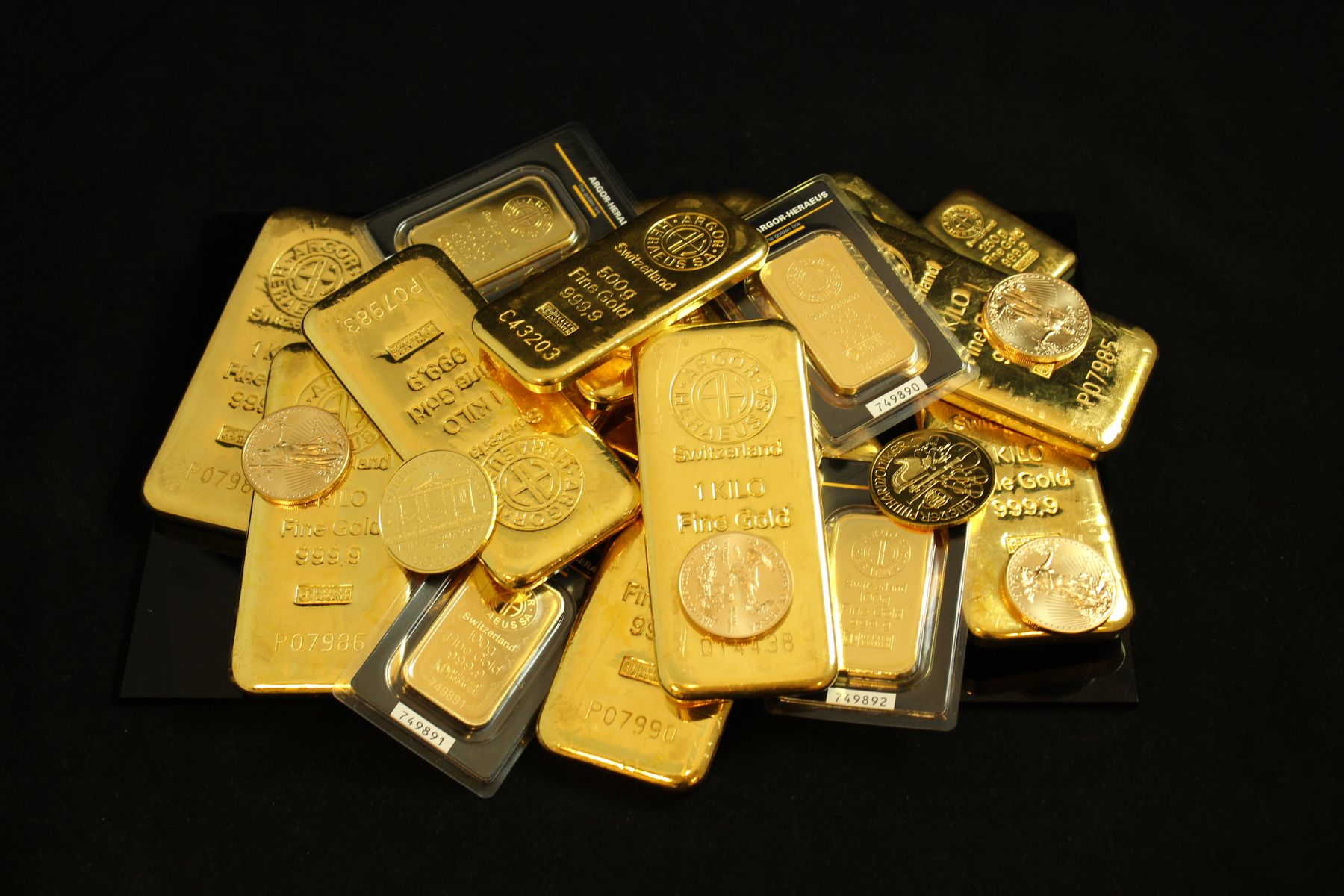 Gold bars and investment coins arranged on a black surface